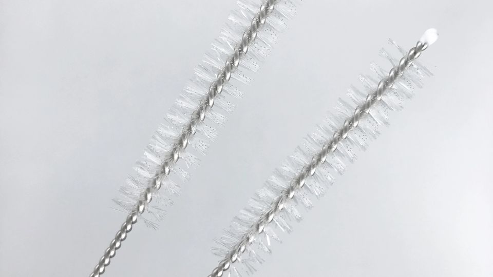 Two nylon straw brushes with twisted wire handles on a white background